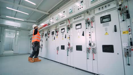 electrical engineer working check the electric current voltage and overload at front of load center cabinet or consumer unit for maintenance in main power distribution system room.