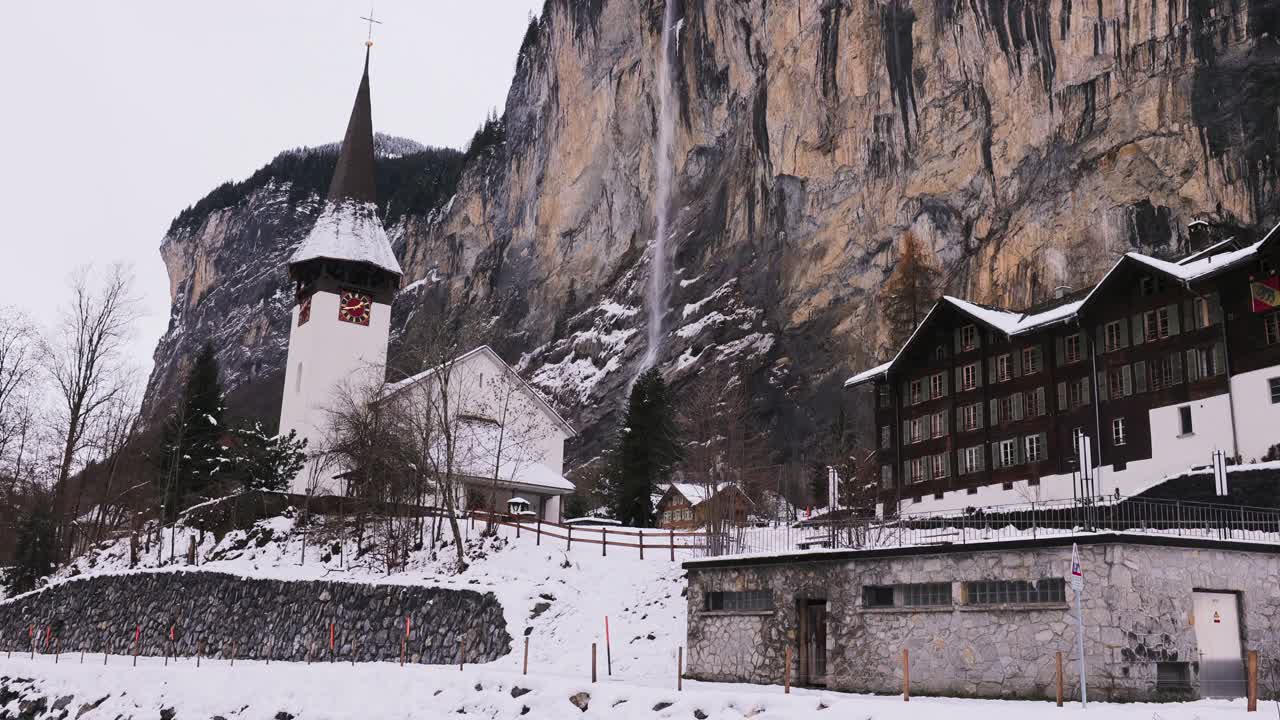 라우터브룬 (lauterbrunnen) 에 있는 슈타우바흐 폭포 (staubbach falls) 의 파닝, 앞면에는 교회와 강이 있다.
