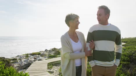 caucasian couple enjoying free time by sea on sunny day walking path