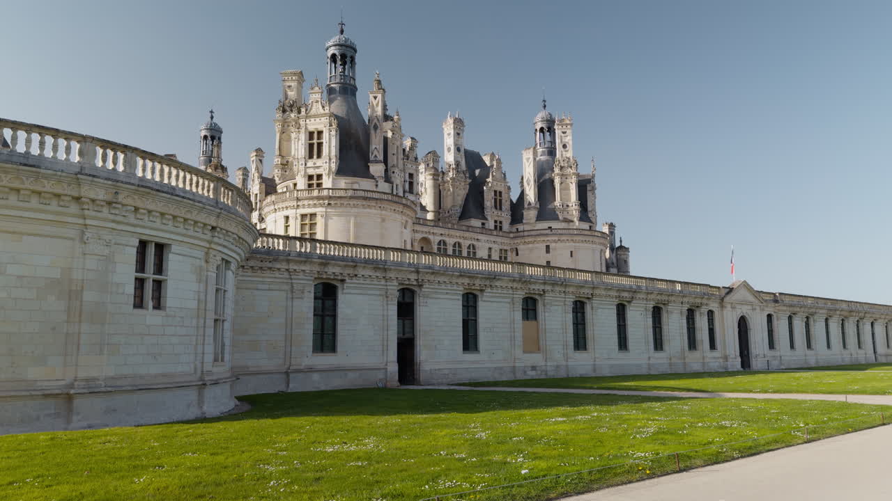 Majestic Renaissance castle with towers, clear sky, and peaceful green lawn view