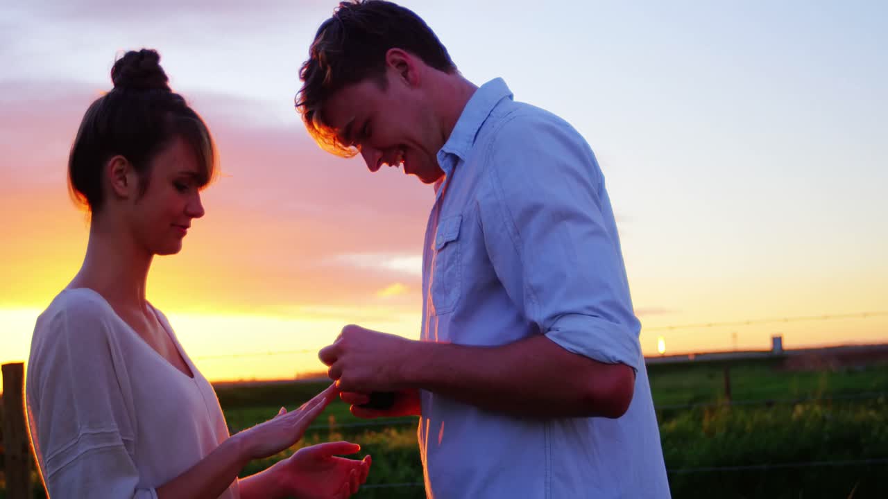 мужчина дает обручальное кольцо женщине в поле