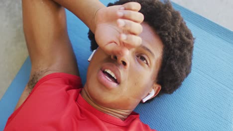 Fit-african-american-man-exercising-at-home-and-resting-tired-at-home