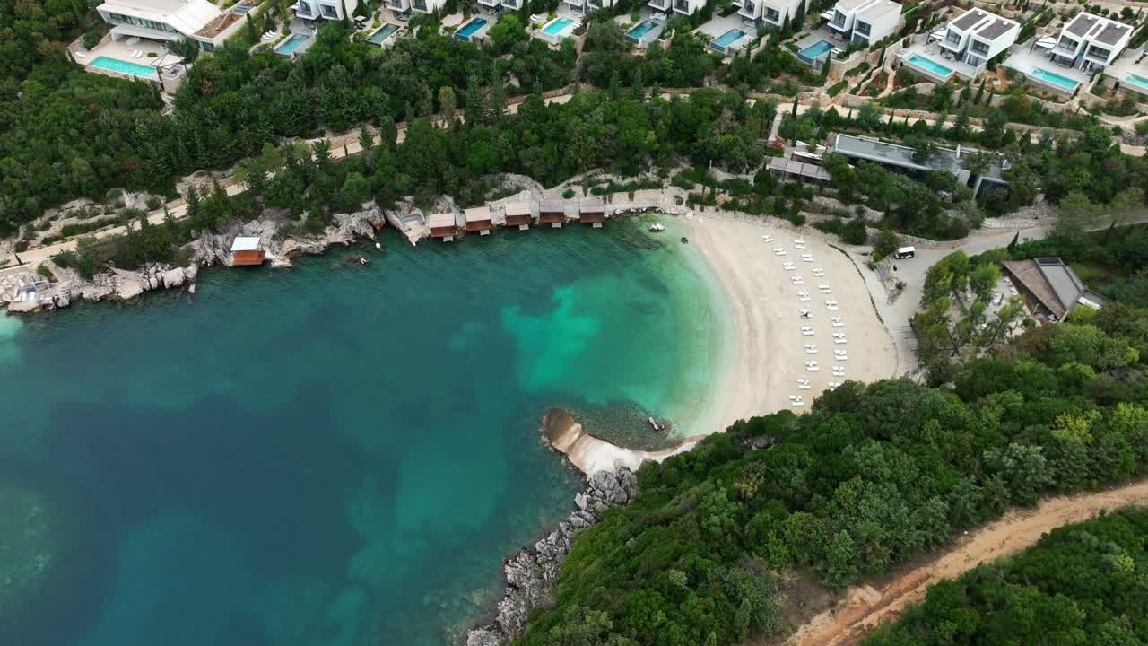 Saranda, Vlorë, Albania - A Hidden Cove With Turquoise Waters, Luxury Villas, and a Quiet, Sandy Beach Lined With Sunbeds - Orbit Drone Shot