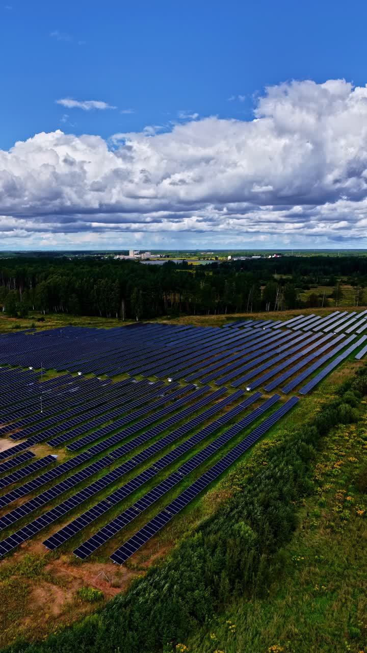 Vertical aerial of solar farm with aligned panels and access roads, industrial energy site, approach
