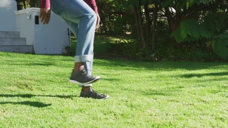 Mittelteil-Eines-Afroamerikanischen-Vaters-Und-Sohnes,-Die-Gemeinsam-Im-Garten-Fußball-Spielen