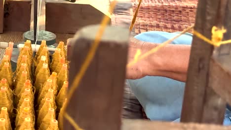 detailed view of vibrant yellow silk threads being woven on a traditional wooden loom.