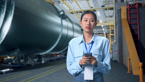 an asian business woman using mobile phone an looking around in pipe manufacturing factory