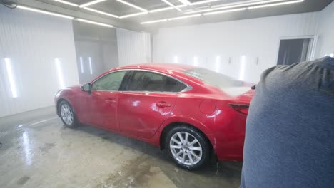 man worker washing red car on a car wash.