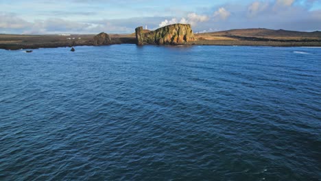 Wunderschöne-Luftaufnahme-Der-Klippen-Am-Meer-In-Island,-Die-Von-Der-Blauen-Ozeanoberfläche-Hochschwenken