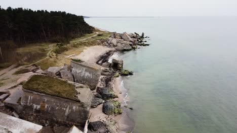 aerial view of abandoned seaside fortification building at karosta northern forts on the beach of baltic sea in liepaja in overcast spring day, wide drone shot moving forward tilt down high