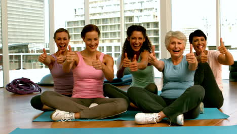 group of women in fitness studio showing thumbs up