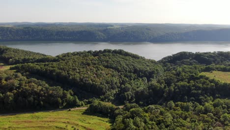 high aerial dolly shot drone flying above trees toward mighty susquehanna river in pennsylvania, summer afternoon shot