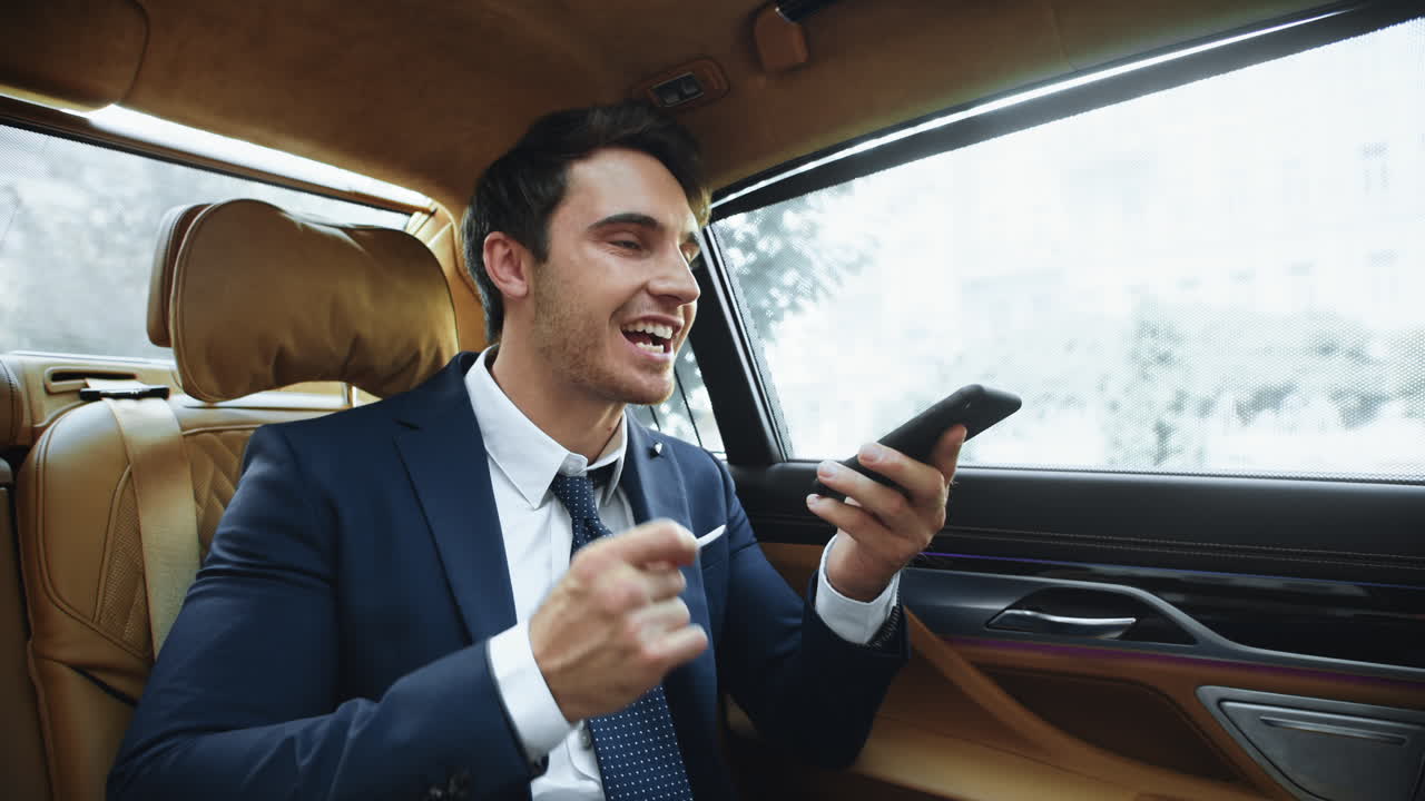 hombre profesional estresado grabando mensajes de voz a un teléfono inteligente en un coche moderno.