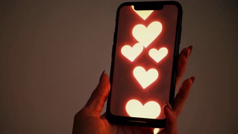 woman holding smartphone with glowing heart icons