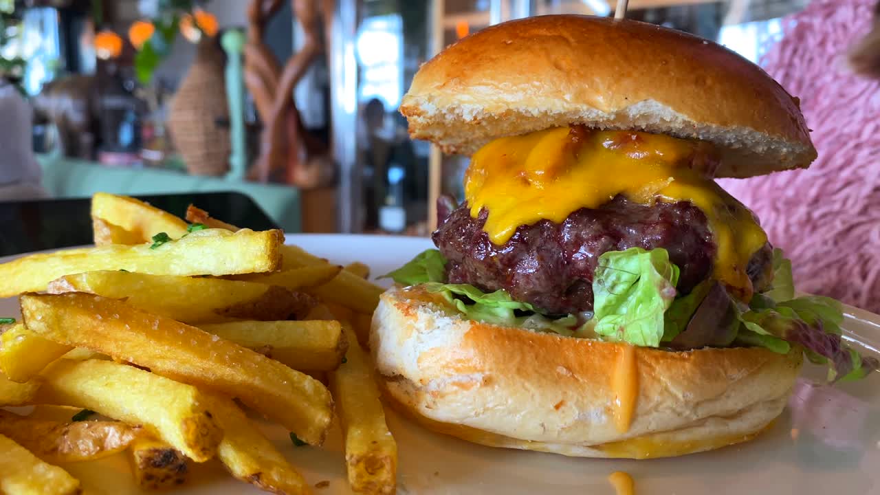 jugosa hamburguesa con queso cheddar, lechuga, bollo de brioche y papas fritas, restaurante de comida rápida, toma de 4k
