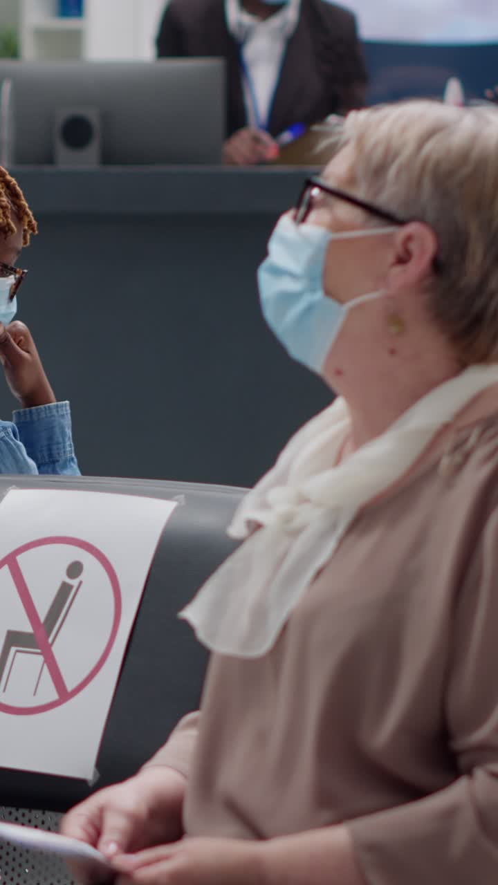 People wearing face masks and practicing social distancing in a waiting room