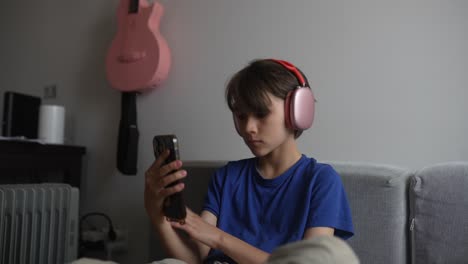 boy using smartphone while wearing headphones