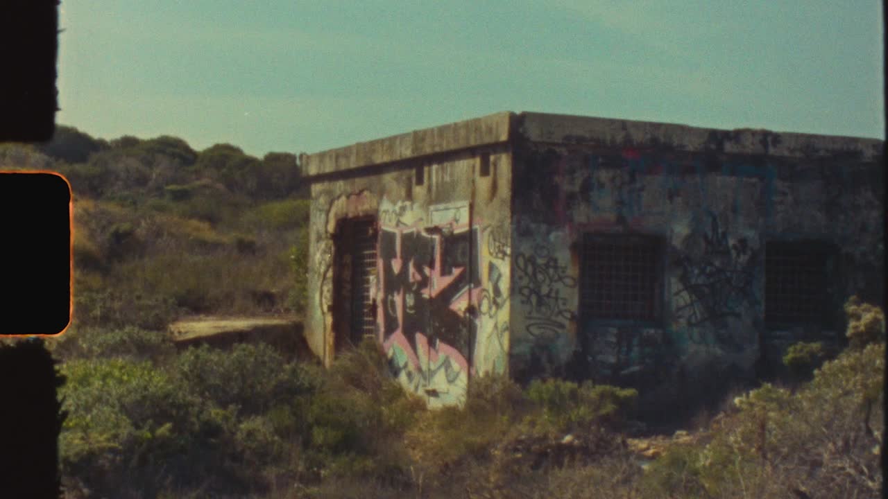Abandoned Building Covered in Graffiti in an Overgrown Landscape