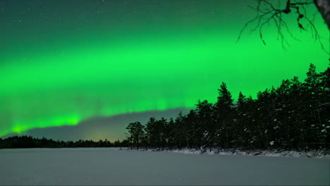 green bands of aurora northern lights grow and rise to peak over icy lake