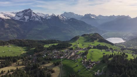 Breathtaking-drone-shot-of-the-Walensee-Lake-and-the-villages-of-Weesen,-Amden-and-Quinten-in-Switzerland,-showing-ice-capped-mountain-ranges,-part-of-the-lake,-green-hills,-trees-and-villages