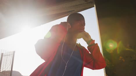 focused african american man putting earphones on before exercising outdoors by the sea