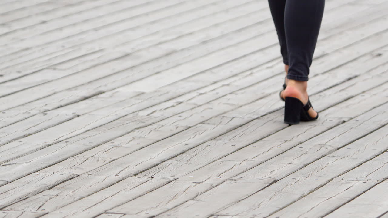 Close-up of a woman's feet in high heels on a wooden boardwalk