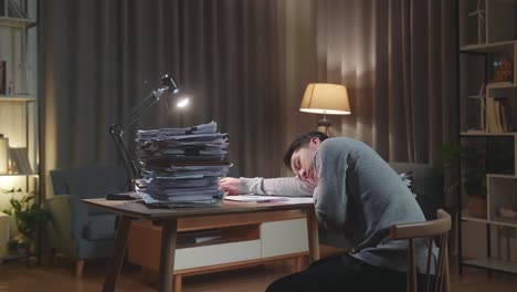 back view of tired asian man sleeping due to working hard with documents at home