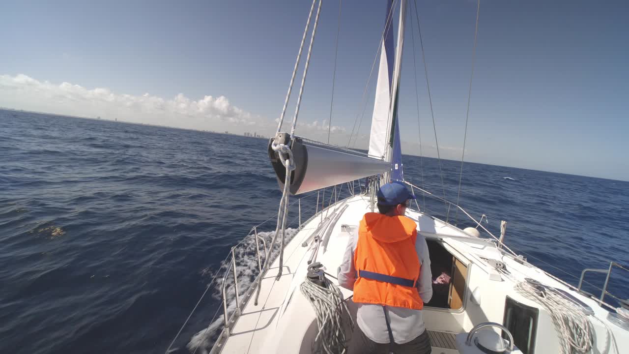 Sailor Fixes The Hull Rope Of A Motorboat Navigating The Bahamas Beach. wide shot, rear