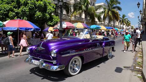 purple convertible car in a cuban market