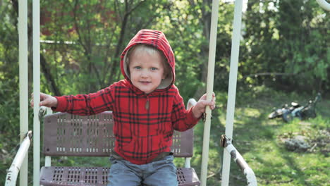 niño sonriente en columpio en día soleado