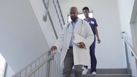 african american male and female doctors walking stairs at hospital