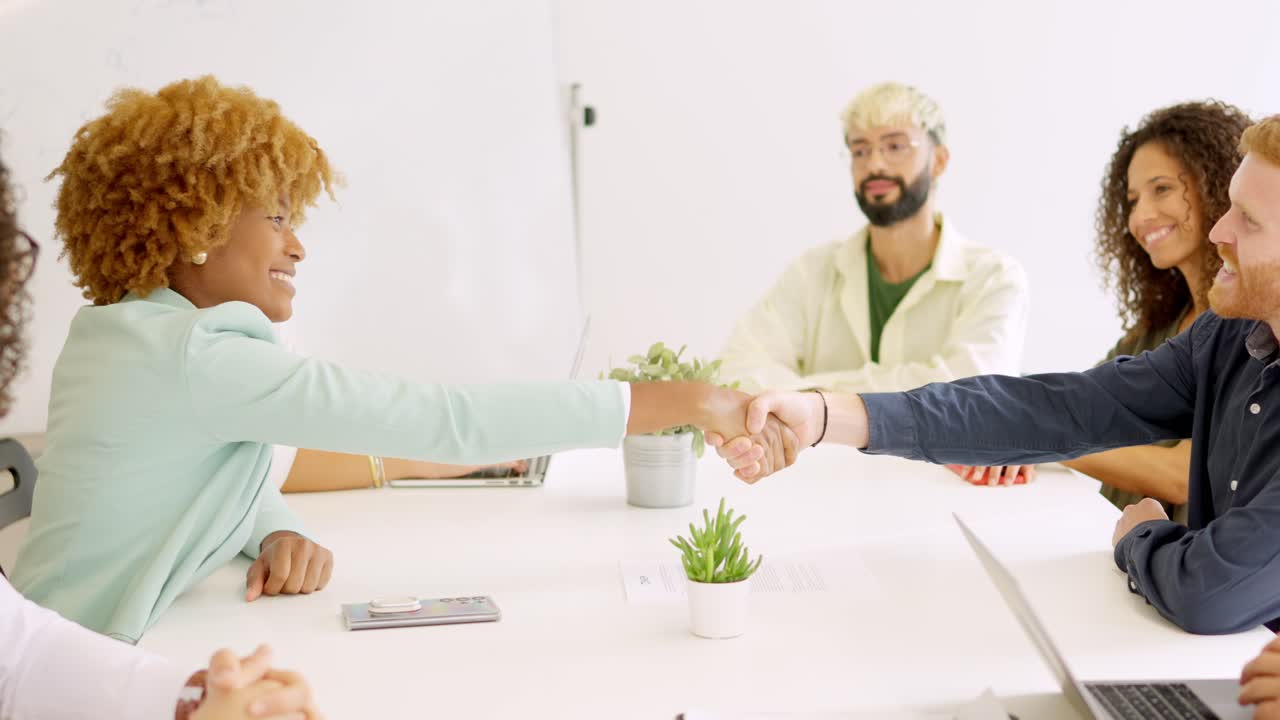 Business people handshaking sitting on a table with multi-ethnic coworkers