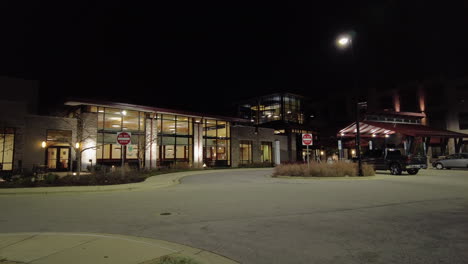 hospital por la noche, con algunos autos en el estacionamiento