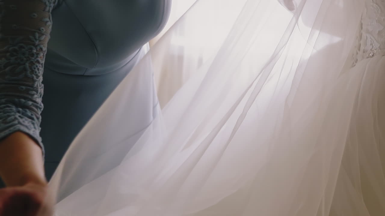 mother adjusts lacy veil of young daughter in wedding dress