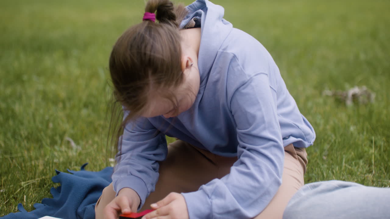 다운 증후군 을  ⁇ 고 있는 작은 소녀 가 공원 에 앉아 있는 나무 탑 을 짓고 있는 클로즈업 전망