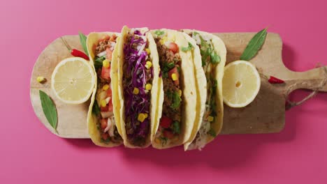 video de tacos recién preparados a bordo sobre un fondo rosado