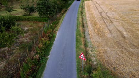 coche cruzando la carretera rural en piamonte, cerca de la pequeña ciudad de castagnole delle lanze, italia