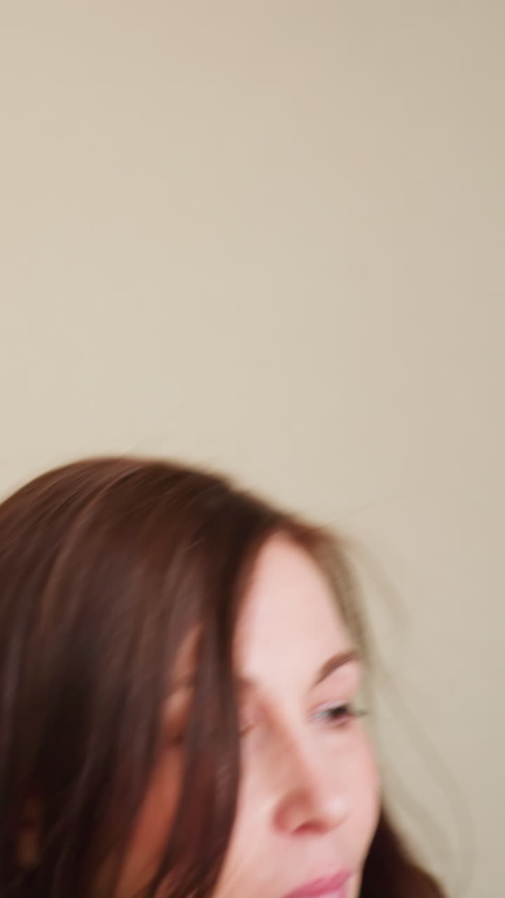 Close-up of businesswoman in gray blazer walking through office hallway with calm expression and closed eyes, suggesting moment of reflection, confidence, or composure in quiet professional setting