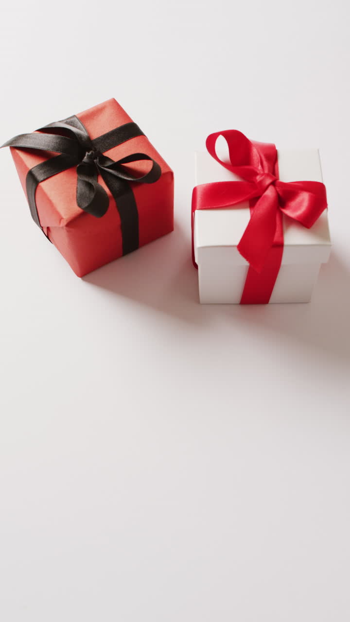 video vertical de cajas de regalos blancas y rojas atadas con arcos, sobre un fondo blanco con espacio para copiar