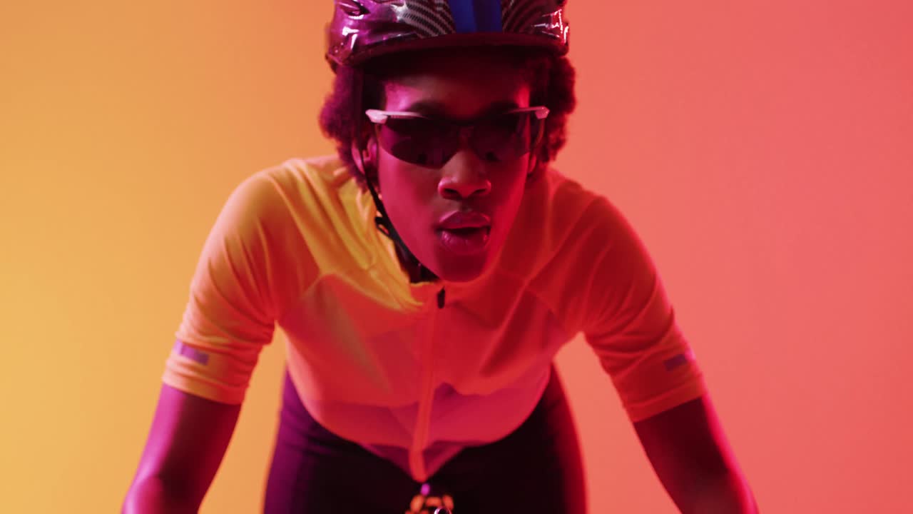 video de una ciclista afroamericana enfocada montando en un rayo naranja de neón
