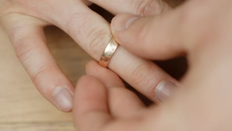 a close-up of a hand delicately placing a golden ring on the right ring finger, capturing a meaningful and intimate moment.