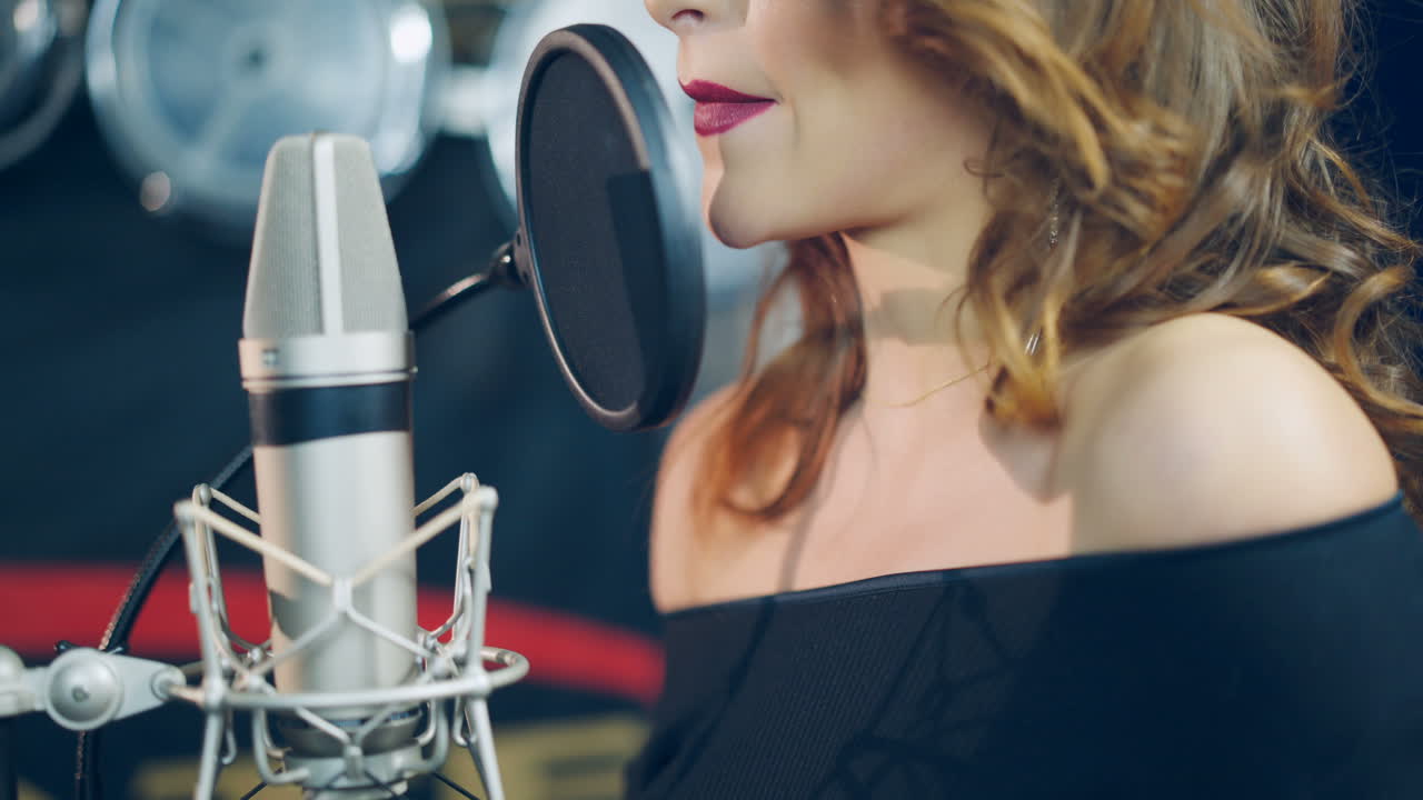 Professional musician recording new song or album in studio. Woman singing in the recording studio.