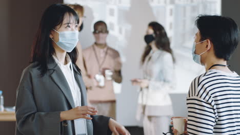 asian women in masks talking on business event