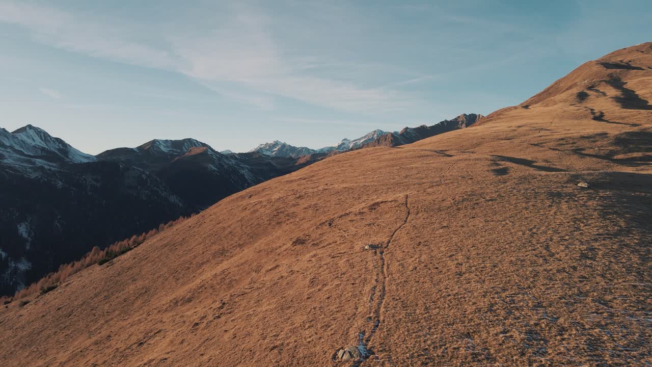 Sorvolando un escursionista che cammina su una collina e rivelando un panorama montano