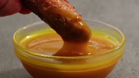dipping a chicken wing into sauce