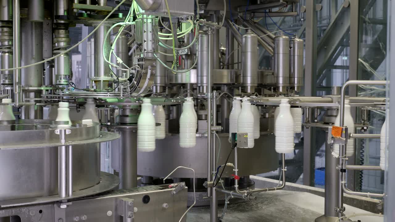 una toma en movimiento de una línea de producción de leche, las botellas se llenan de leche y luego se sellan herméticamente