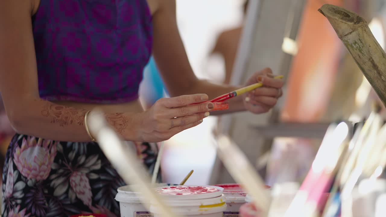 Close-up of a person painting with a brush and colorful paints