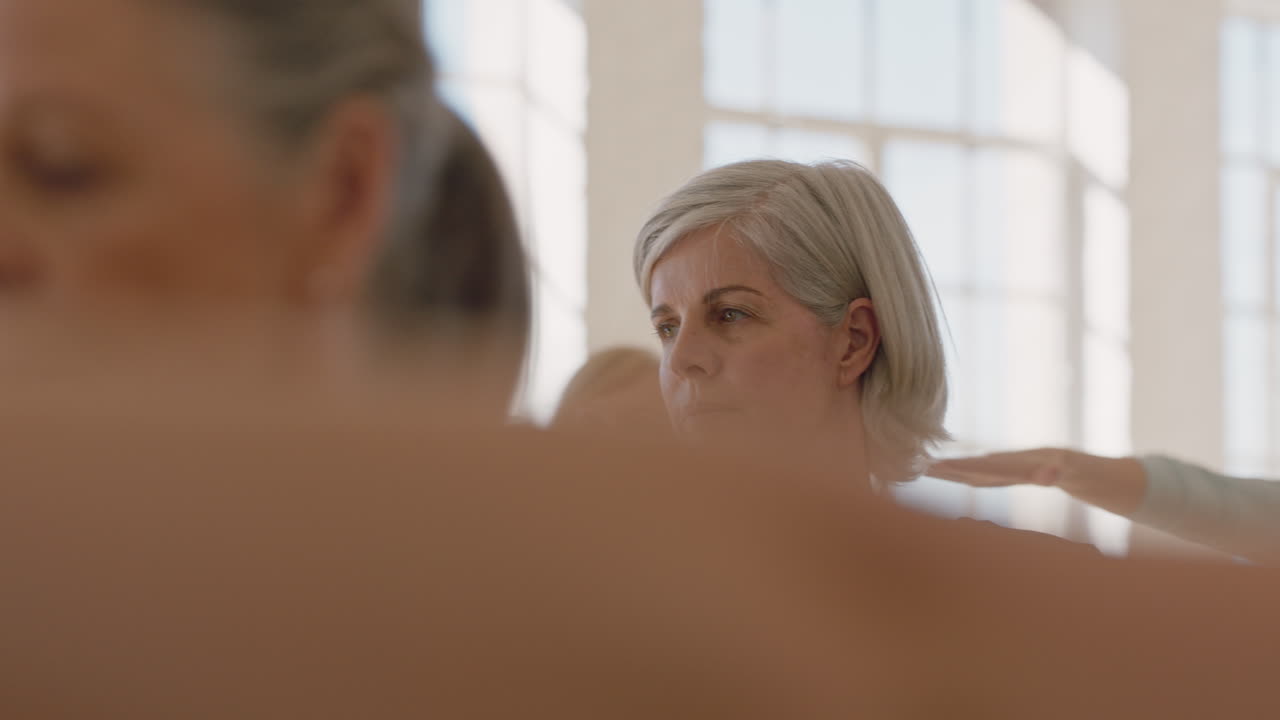 занятие йогой здоровых зрелых женщин, практикующих позу воина, во время утренней фитнес-тренировки в студии