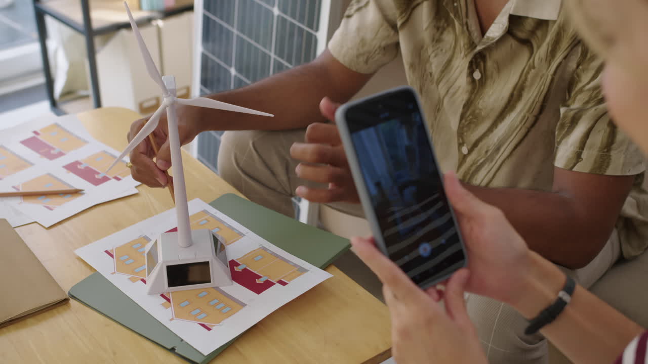 Woman Filming Video How Man Explaining Work of Wind Turbine on Model