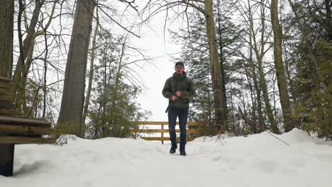 Young-Male-Hiker-with-backpack-walks-away-from-view-point-in-winter-forest